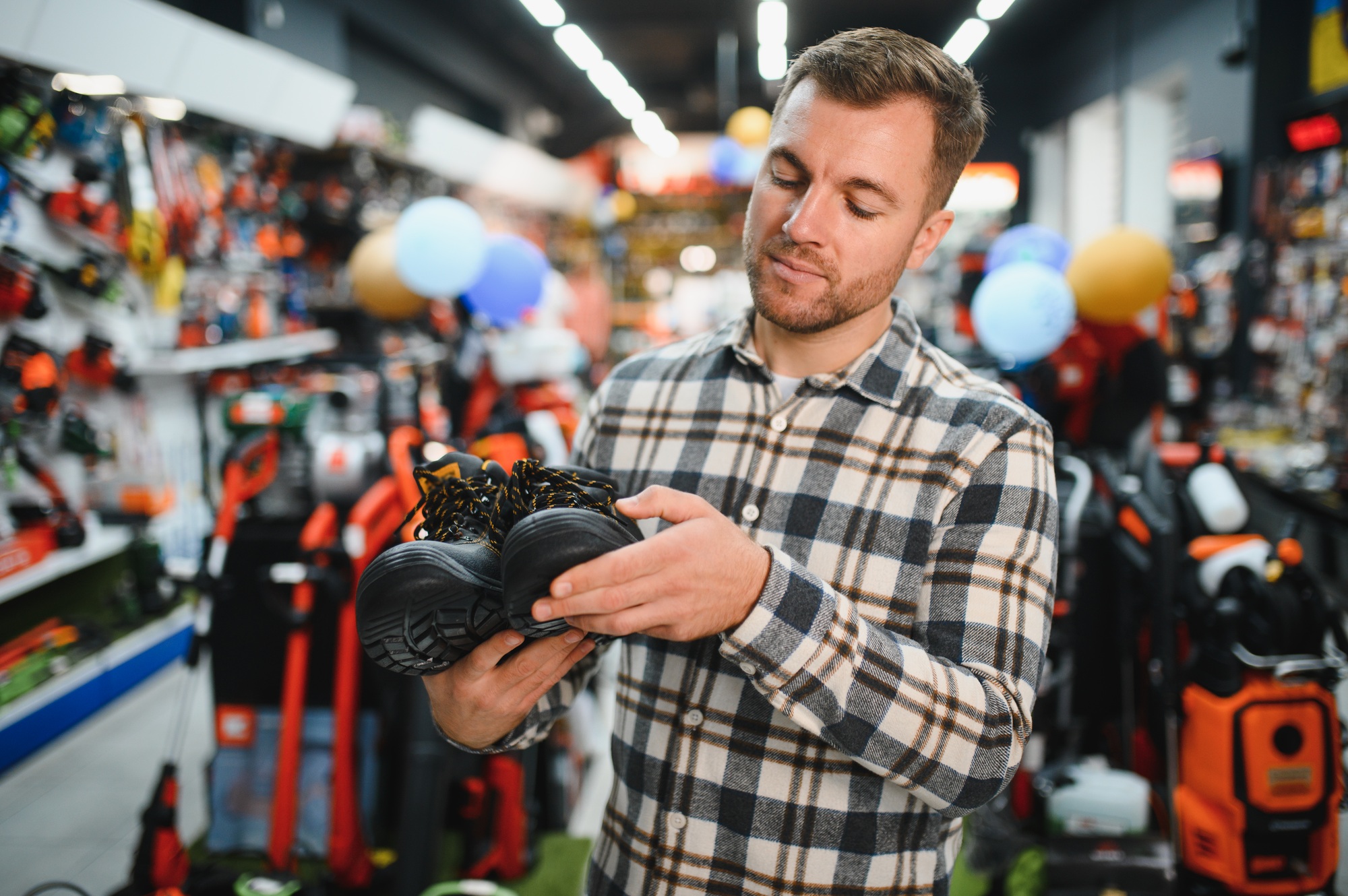 a man in a hardware store chooses safety shoes for construction work