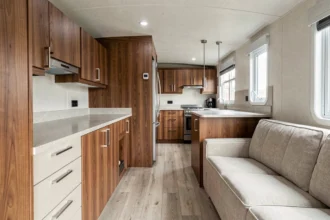 Intérieur d'un mobil-home haut de gamme avec finitions bois et métal brossé, illustrant la qualité de fabrication d'un constructeur premium