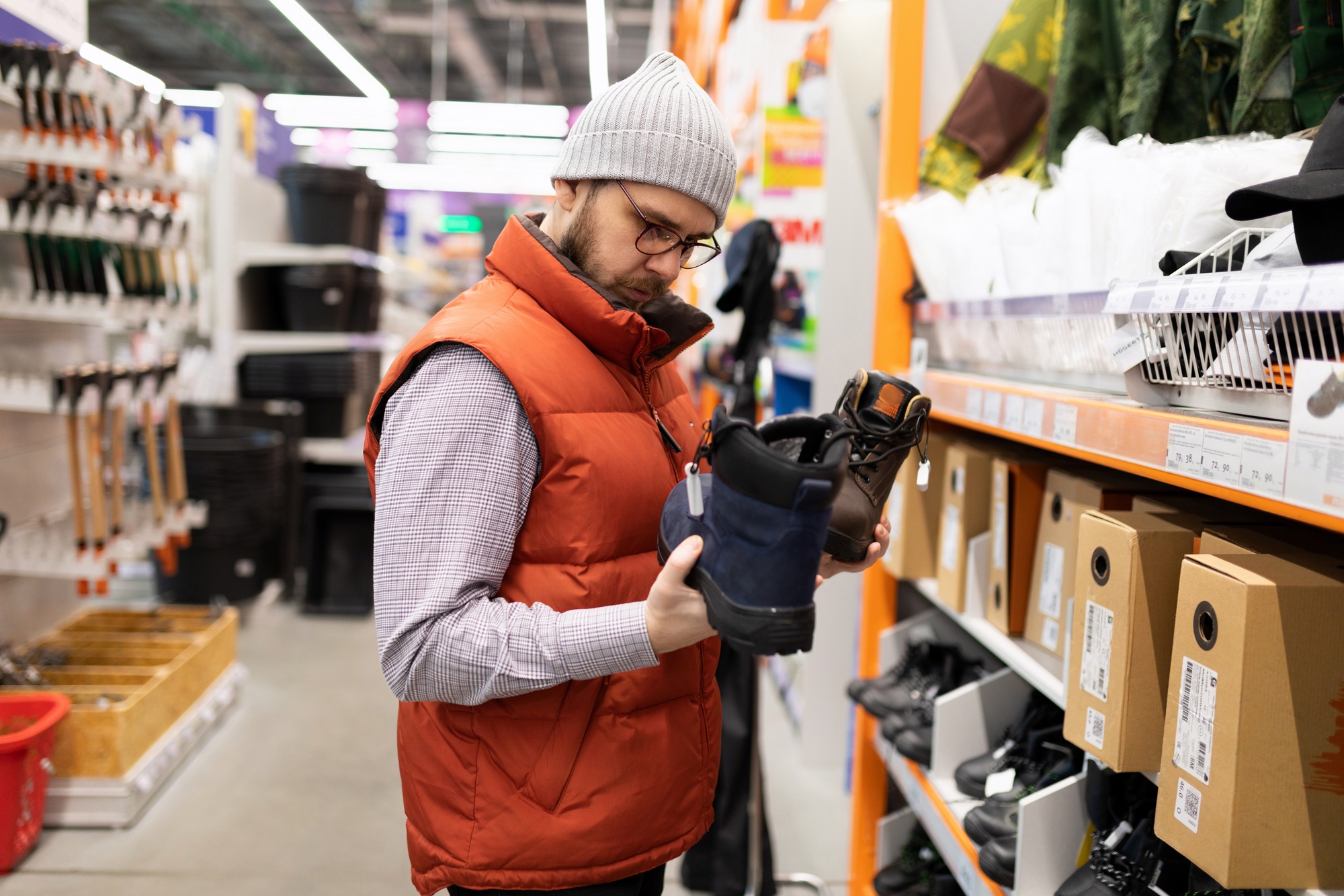male builder in a hardware store picking up new safety shoes