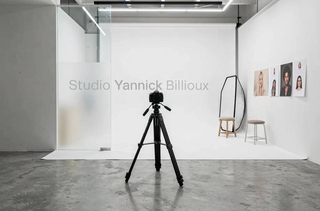 Intérieur du Studio Yannick Billioux avec cyclorama blanc, trépied et exemples de portraits accrochés au mur