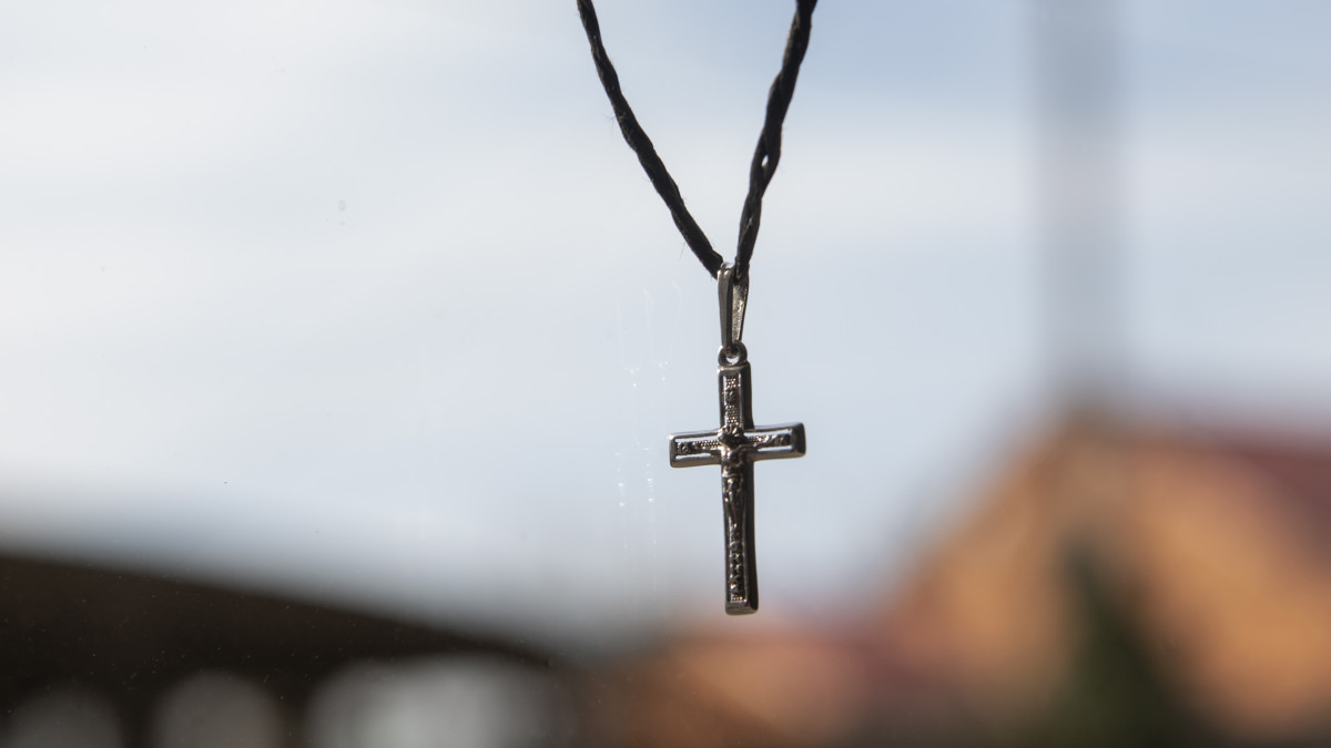 un collier avec un pendentif en forme de croix religieuse sur un fond flouté clair